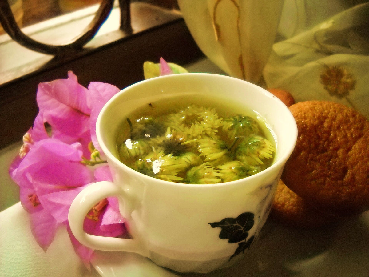 A cup of freshly brewed chrysanthemum tea, pale gold in color, showing the ideal result of correct brewing technique