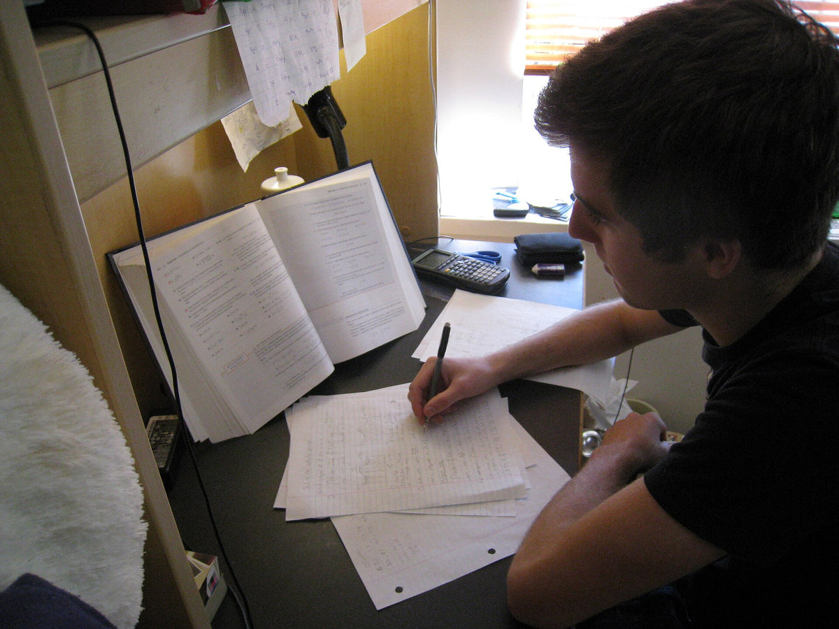 A person studying at a desk with an open book, the kind of focused work supported by L-theanine and caffeine in tea